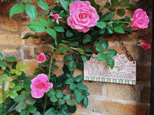 Close up Welcome sign on a brick wall decorated with roses photo