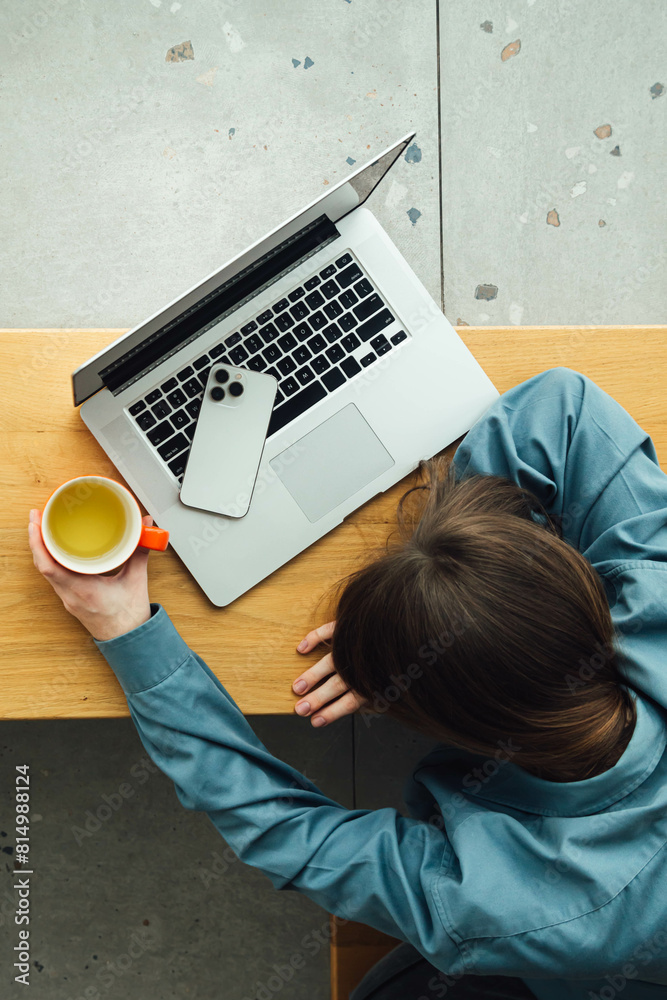 A tired woman lies face down in front of a laptop with a cup of tea. A tired woman lies face down in front of a laptop with a cup of tea.