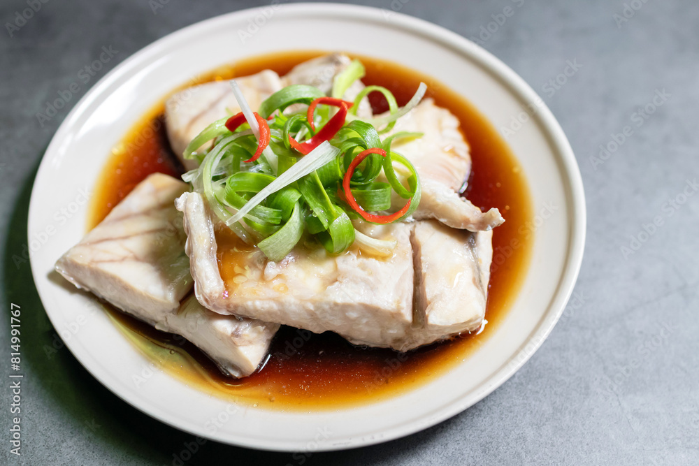 Sea bass fillet steam with soy sauce. Top view on black table background.