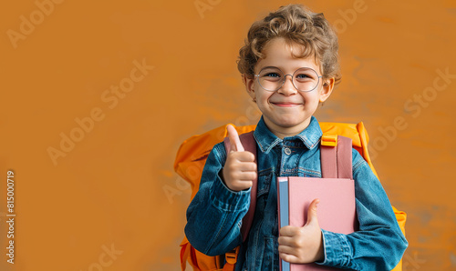 Happy Schoolboy With Backpack and Book Giving Thumbs Up, Cheerful Child Ready for School, Smiling Boy in Glasses and Denim Attire photo