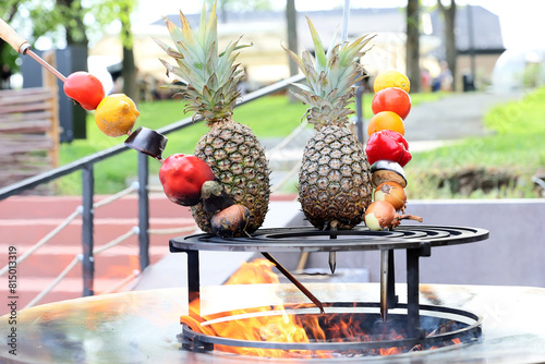 Pineapple,green pepper,tomato, lemon and onion they are placed on a cast iron grill to be cooked. © Silviu