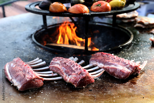Raw fresh rack of lamb are placed on a cast iron grill to be grilled. © Silviu