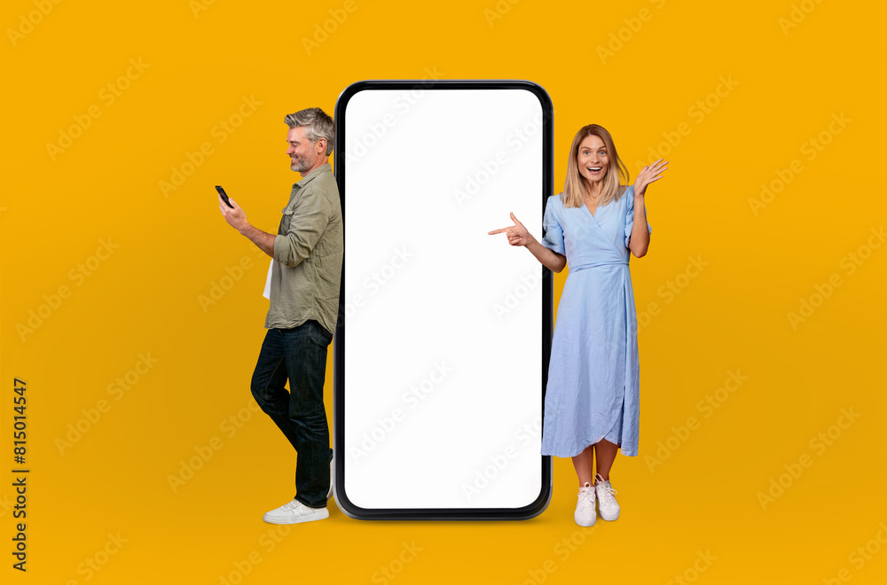 Mature man and woman are standing together next to a huge telephone, appearing to be engaged in a conversation or perhaps waiting for a call Mature man and woman are standing together next to a huge telephone, appearing to be engaged in a conversation or perhaps waiting for a call