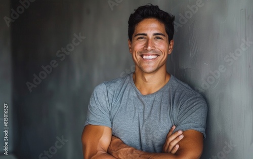 Cheerful man in a gray t-shirt, smiling with arms crossed.