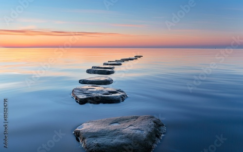 Smooth stones on calm water at sunset  creating a serene path.