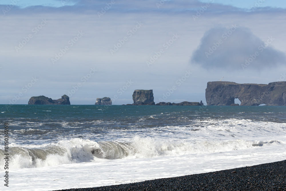 waves crashing at the black sand beach of Reynisfjara with an stunning mountain range in the distance, Iceland