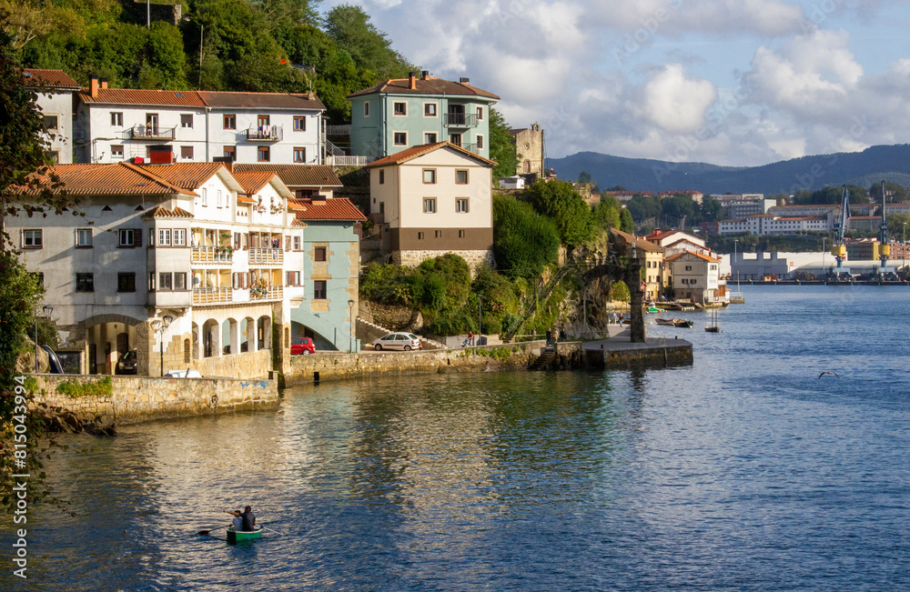 Pueblo pesquero del pais vasco visto en alto desde el mar con padre e hijo en barca a remo
