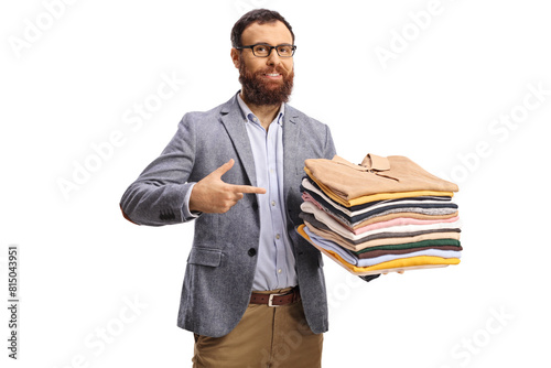 Bearded man pointing at a pile of folded clothes and smiling at camera