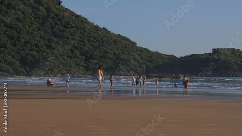 People walking and resting on sandy beach along sea during warm sunny evening in Agonda 