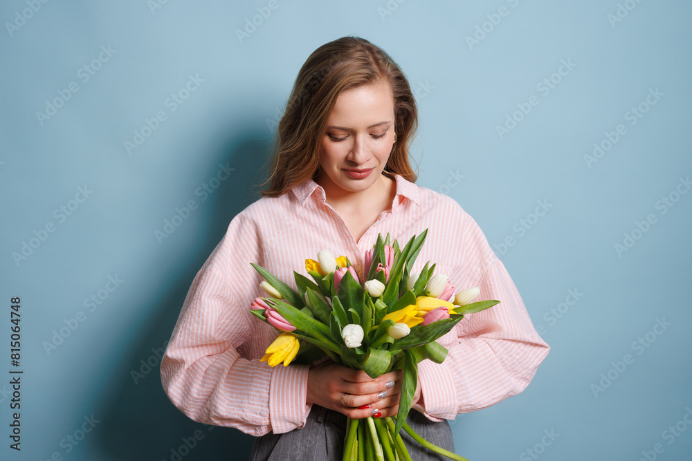 girl with a spring bouquet of tulips on a clean blue background, spring flowers