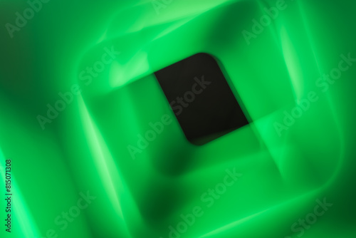 Black square on green satin cloth, abstract background, close up