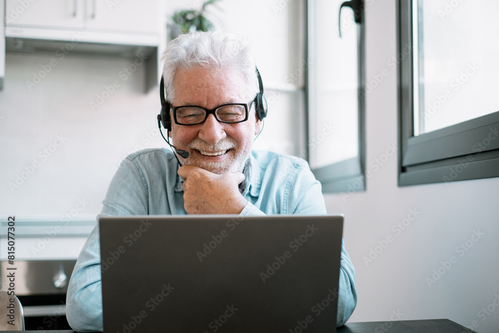 Video call concept.  Senior caucasian businessman smiling working online watching webinar podcast on laptop and learning education course conference calling sit at home desk, remote working