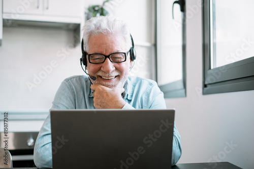 Video call concept. Senior caucasian businessman smiling working online watching webinar podcast on laptop and learning education course conference calling sit at home desk, remote working