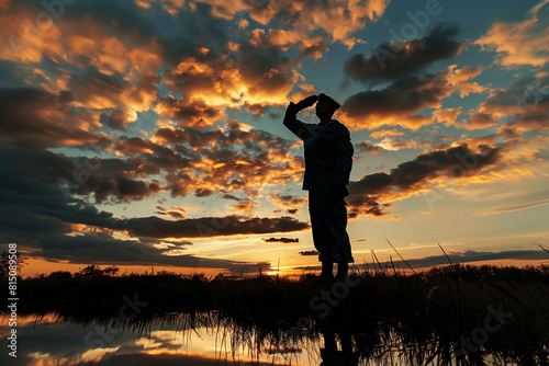 Dramatic sky backdrop with silhouette of a Navy veteran saluting, Memorial Day. photo