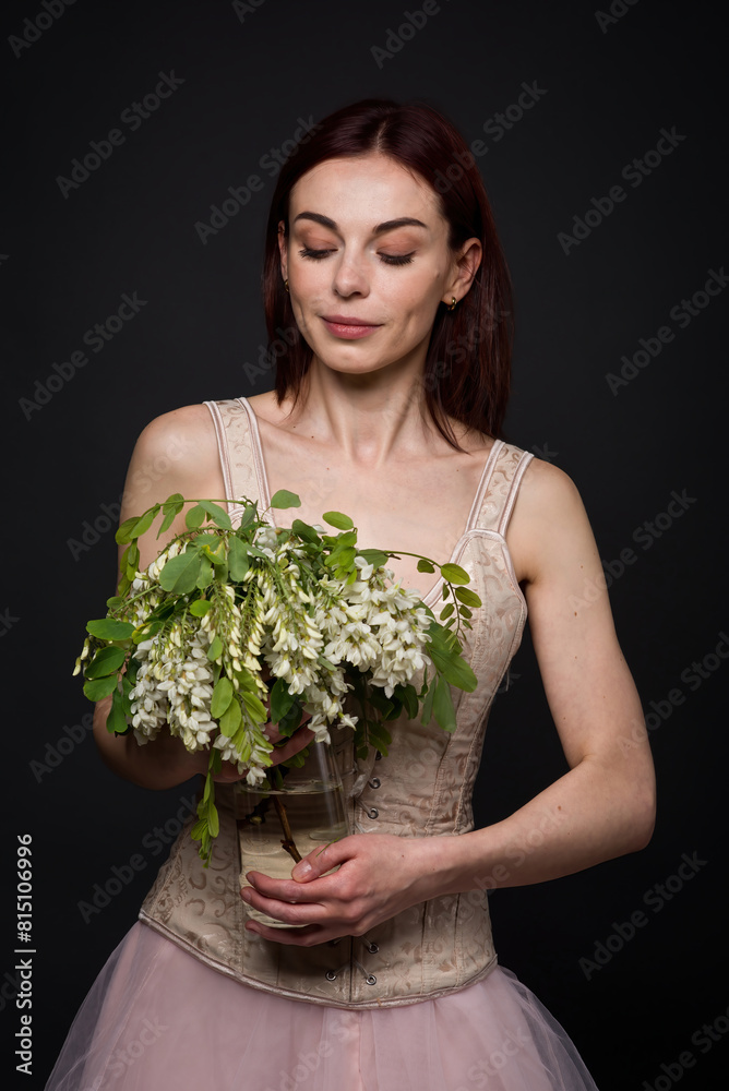 A captivating woman poses in a photo studio with an acacia branch. A captivating woman poses in a photo studio with an acacia branch.