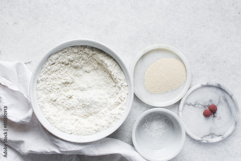 Mise en place of ingredients for making bread, All purpose flour salt and yeast on a marble countertop, process of making bread Mise en place of ingredients for making bread, All purpose flour salt and yeast on a marble countertop, process of making bread