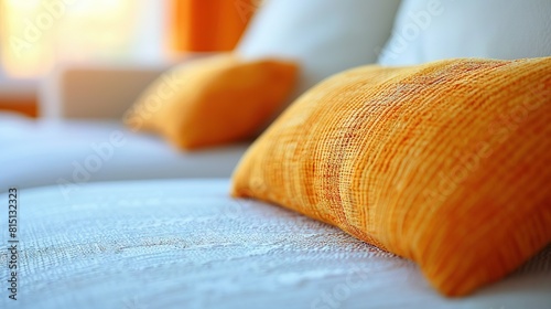   A close-up of a white and orange comforter on a bed with two orange pillows on top