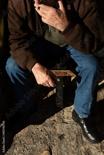 Hombre anciano sentado fumándose un cigarro.