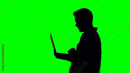 Male developer freelancer or it engineer working outdoor using laptop in silhouette at sunset. Hardly working evening. Adorable dusk at background. High quality green screen
