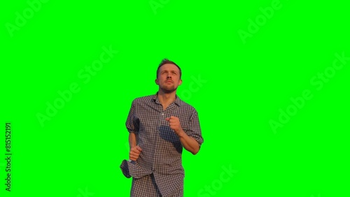 Bearded caucasian male in nightwear running outdoor looking forward. Morning exercise concept. Clear blue sky at background. High quality green screen