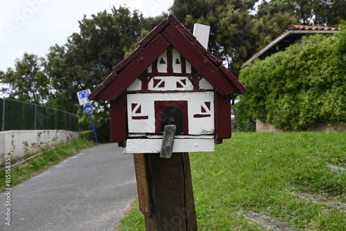 Charming Mailbox: White and Red House-Shaped Letterbox Adorning Exterior Home - Adding Quaint Appeal to Residential Property