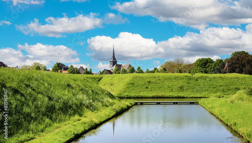 Medieval earth, green pasture and water wall of historical fortified village with church - Stevensweert, Netherlands