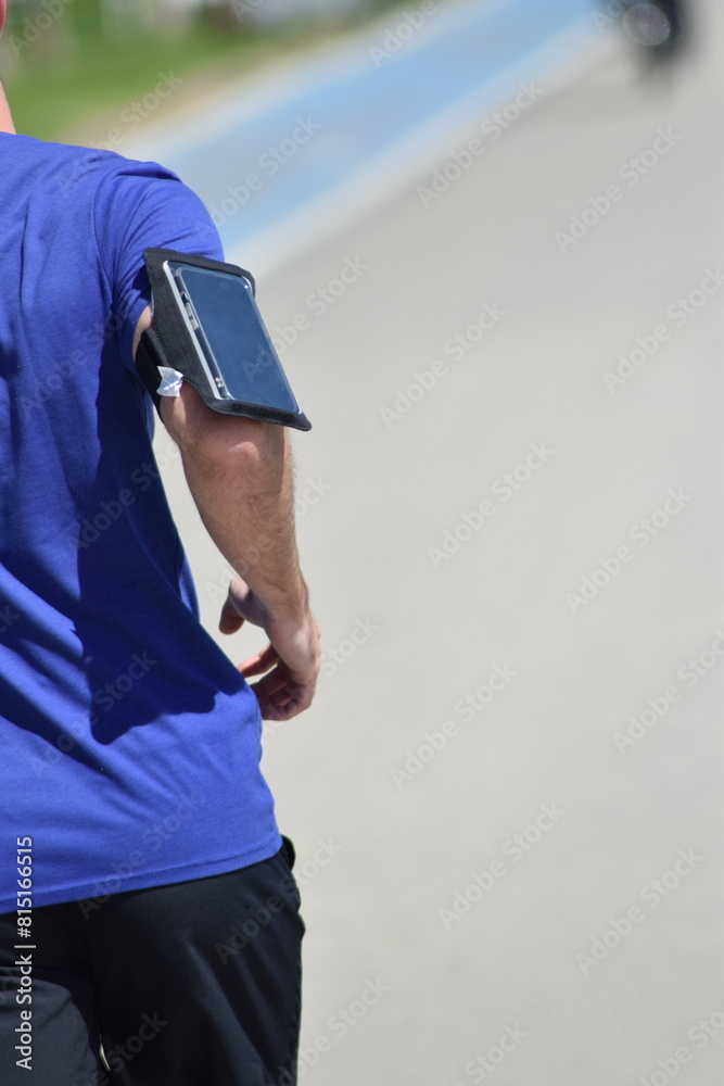 Fototapeta premium Athlete jogging with a bandage and a phone on her arm