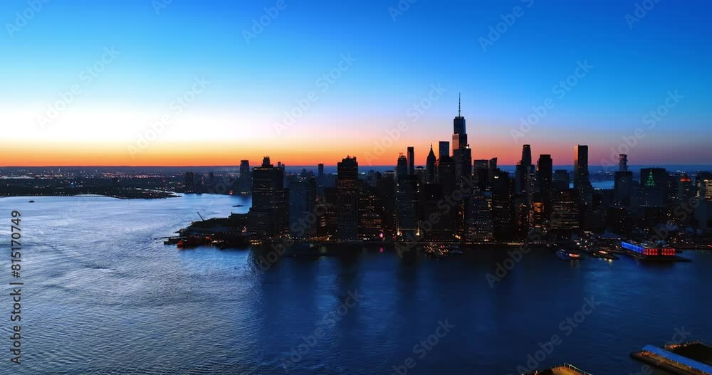 Manhattan switching on lights in the evening. Beautiful scenery of New York with blue-orange sky at backdrop.