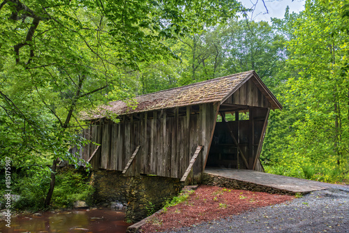 Horizontal, Pisgah covered bridge, A historic wooden bridge with a shake shingle roof, built 1911 spans the West Fork of Little River. Asheboro, Randolph County, NC. late spring, greenery everywhere.  photo