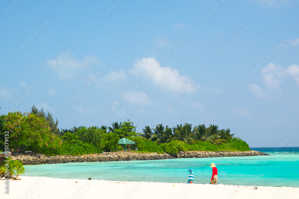 Tourists walking on the beach in Mathiveri Island, with palm trees on the background Tourists walking on the beach in Mathiveri Island, with palm trees on the background