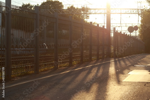 Wallpaper Mural An iron fence separating the railway from the street. The setting sun, shadows on the asphalt. Torontodigital.ca