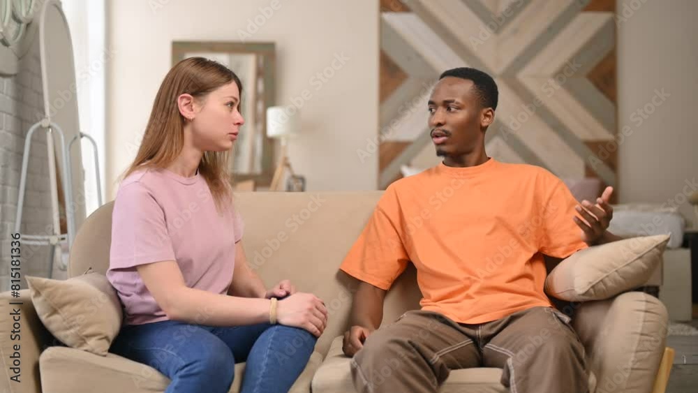 Young people arguing on the sofa at home. A young woman scolds and humiliates her partner, who can only make excuses and listen to dissatisfaction Young people arguing on the sofa at home. A young woman scolds and humiliates her partner, who can only make excuses and listen to dissatisfaction