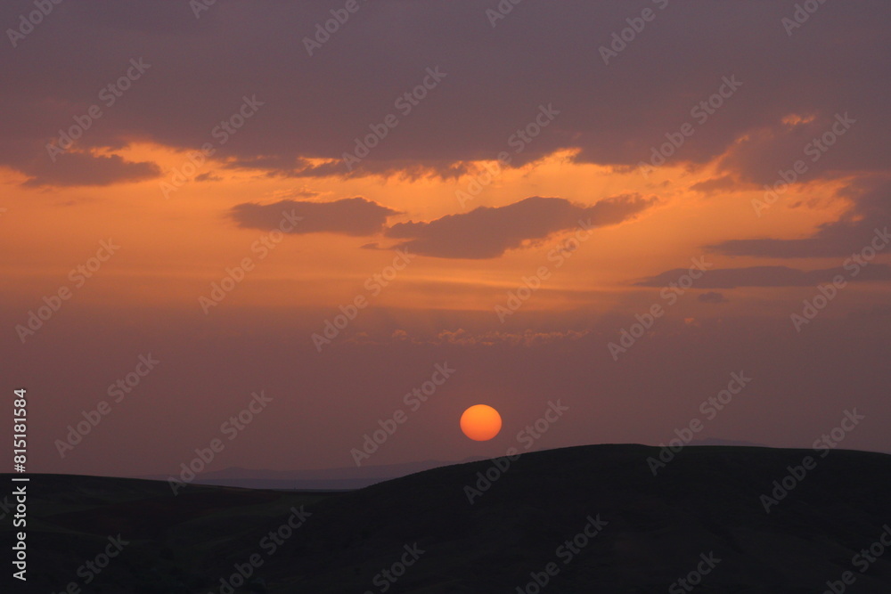 a sunset with clouds and a orange sun setting in the sky. a sunset with clouds and a orange sun setting in the sky.