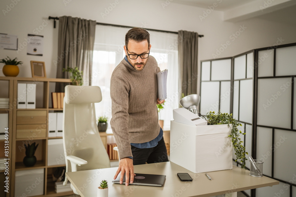 Adult unhappy man pack his stuff at office after he fired from job Adult unhappy man pack his stuff at office after he fired from job