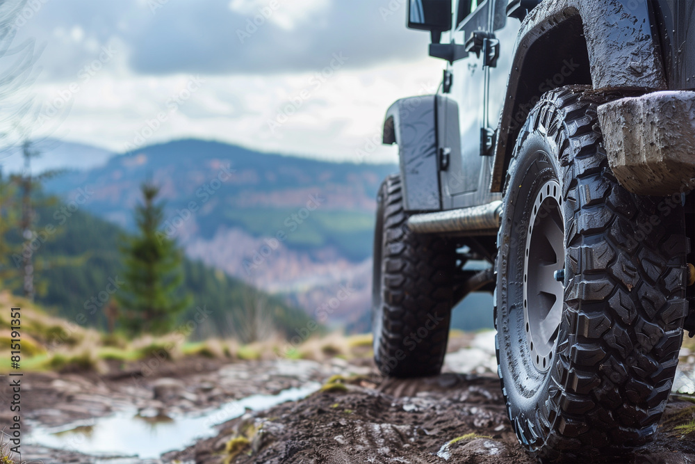 SUV wheel on the off-road adventure trail against the backdrop of mountains in the clouds