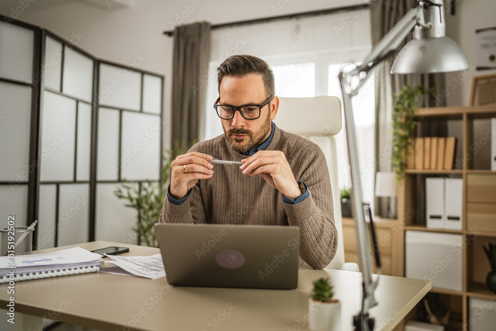 One adult man sit at office and look, read document on laptop at office One adult man sit at office and look, read document on laptop at office