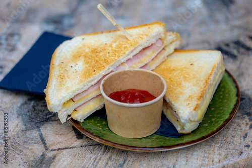 Foto Toasted ham and cheese sandwich in the plate served with tomato ketchup sauce on the side, The tosti in Netherlands or croque-monsieur is a hot sandwich made with ham and cheese