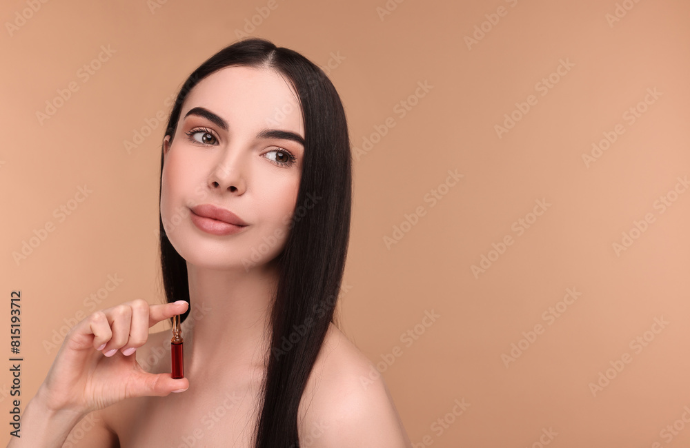 Beautiful young woman holding skincare ampoule on beige background. Space for text Beautiful young woman holding skincare ampoule on beige background. Space for text