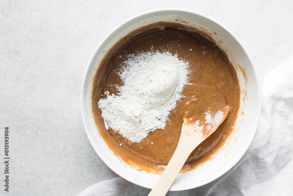 Flour being folded into sugar cookie dough, process of making sugar cookies in a white mixing bowl Flour being folded into sugar cookie dough, process of making sugar cookies in a white mixing bowl