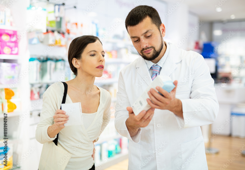 Obraz premium Young adult man pharmacist consulting woman customer about products at pharmacy