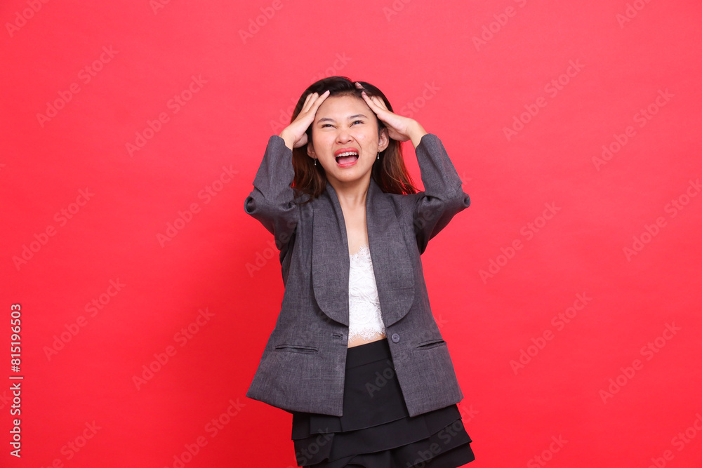 Asian office girl expression severe pain headache both hands holding it candid wearing gray jacket and red background skirt. for health, business and advertising concepts Asian office girl expression severe pain headache both hands holding it candid wearing gray jacket and red background skirt. for health, business and advertising concepts