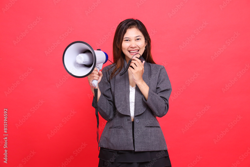 Asian woman leader's expression shouting cheerfully using a megaphone holding a mic to the camera wearing a gray jacket and red skirt. for broadcast, business and advertising concepts Asian woman leader's expression shouting cheerfully using a megaphone holding a mic to the camera wearing a gray jacket and red skirt. for broadcast, business and advertising concepts