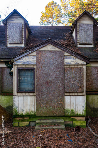 Front of an abandoned house in Chapel Hill, North Carolina, its windows and doors covered in plywood photo