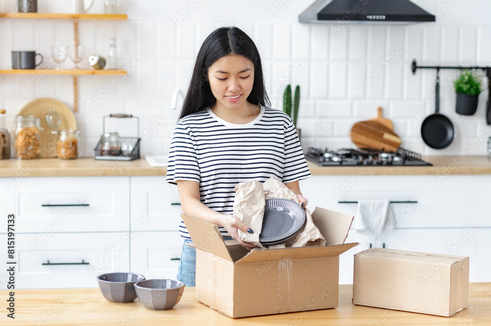 Shopping online or delivery service concept. Happy asian young woman customer at home, opening and unpacking cardboard box carton parcel after buying ordering online Shopping online or delivery service concept. Happy asian young woman customer at home, opening and unpacking cardboard box carton parcel after buying ordering online
