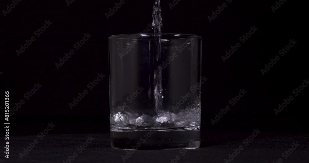 Slow motion shot of water pouring into glass on black background. Slow motion shot of water pouring into glass on black background.