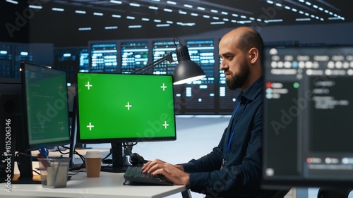 Technician overseeing server room, running code on green screen computer, troubleshooting servers. Software developer upgrading hardware clusters and storage arrays using mockup PC monitor
