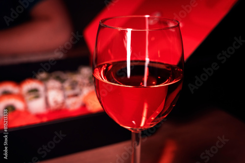 Glass of wine in a red and black setting, take away sushi, date night