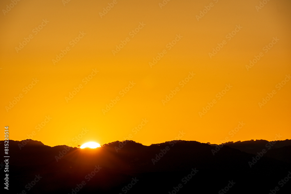 Sunset over the mountains with the sun peaking over the horizon