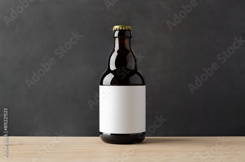 Amber steinie beer bottle mockup with blank label on a wooden table and dark background.