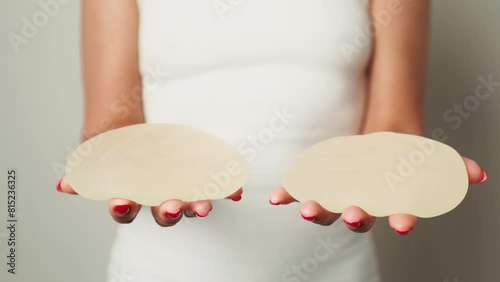 Self-Discovery: Woman Reflects with Removed Breast Implants in Hand photo